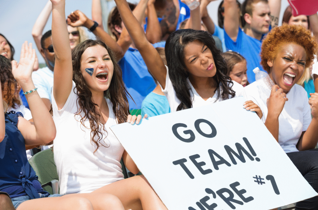 Photo of parents, coaches, and young athletes celebrating together on a sports field, representing the power of community and teamwork in youth sports.
