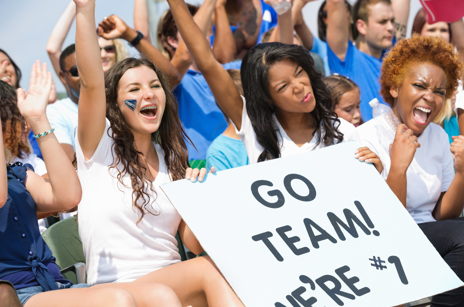 Photo of parents, coaches, and young athletes celebrating together on a sports field, representing the power of community and teamwork in youth sports.